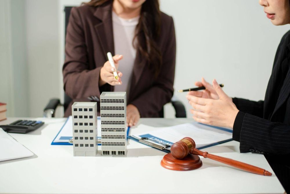 two women sitting at a table with a model of a building