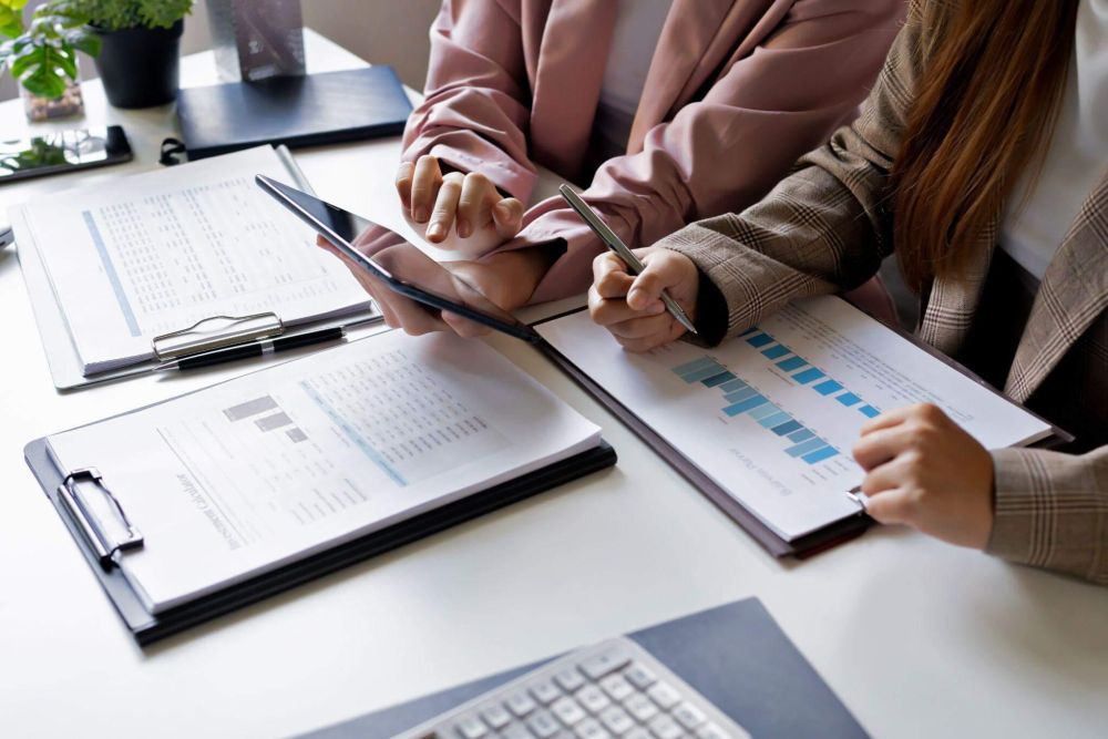 a couple of people sitting at a table with papers