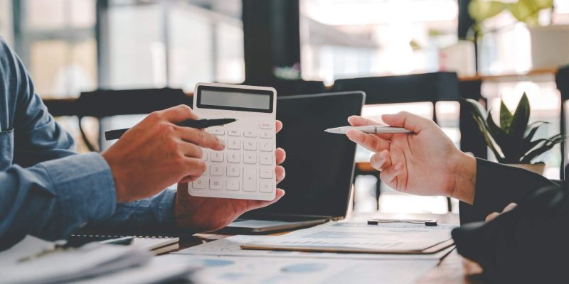 a couple of people sitting at a table with a calculator