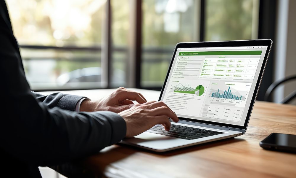 Person analyzing data on a laptop with graphs and charts on the screen in a bright office setting.