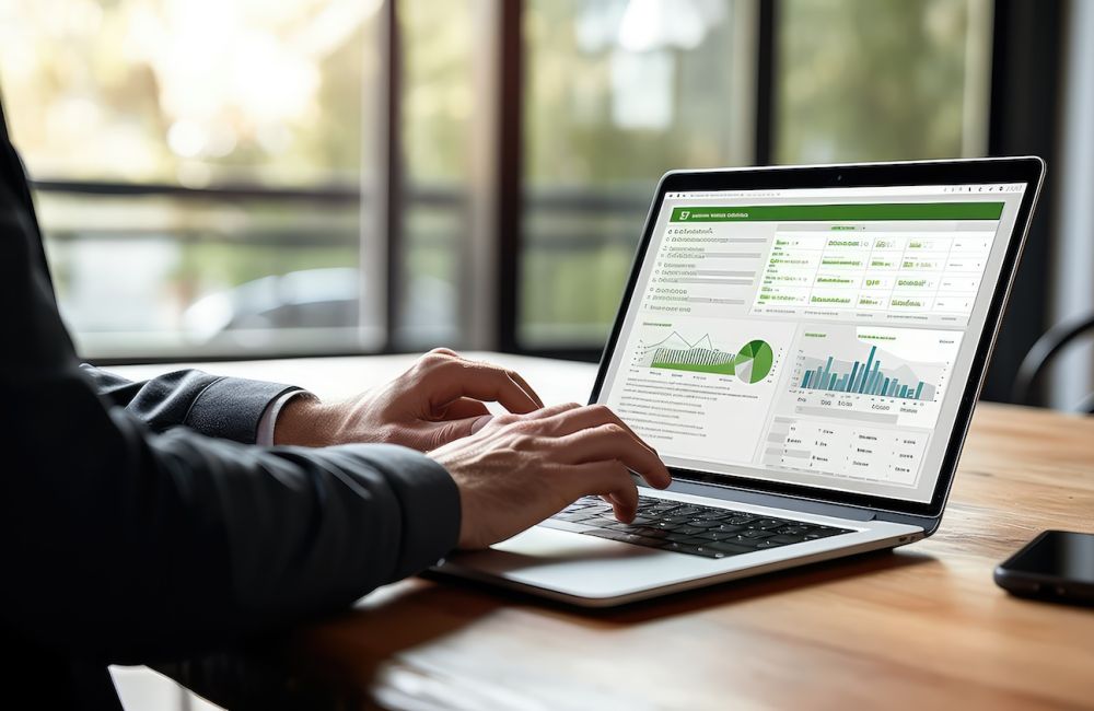 Person analyzing data on a laptop with graphs and charts on the screen in a bright office setting.