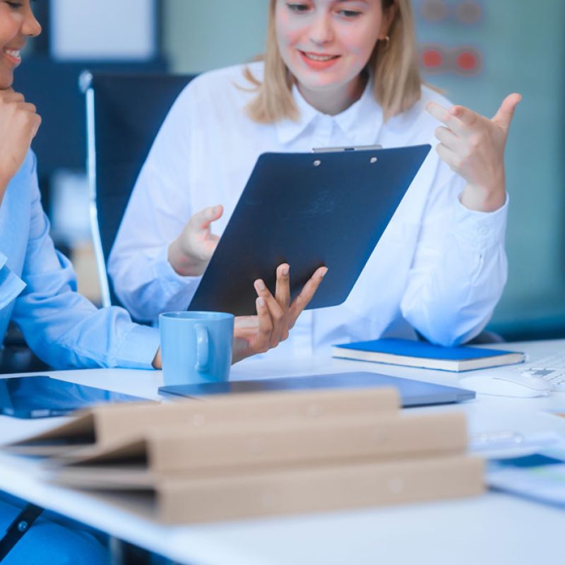 Two professionals discussing paperwork in a bright office setting.