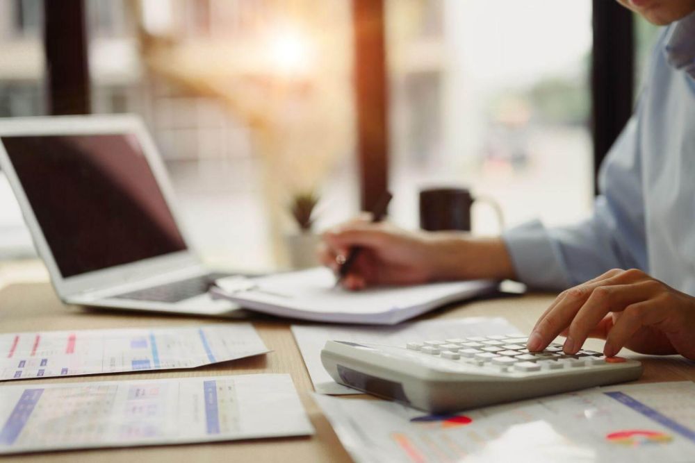 a man sitting at a desk using a calculator