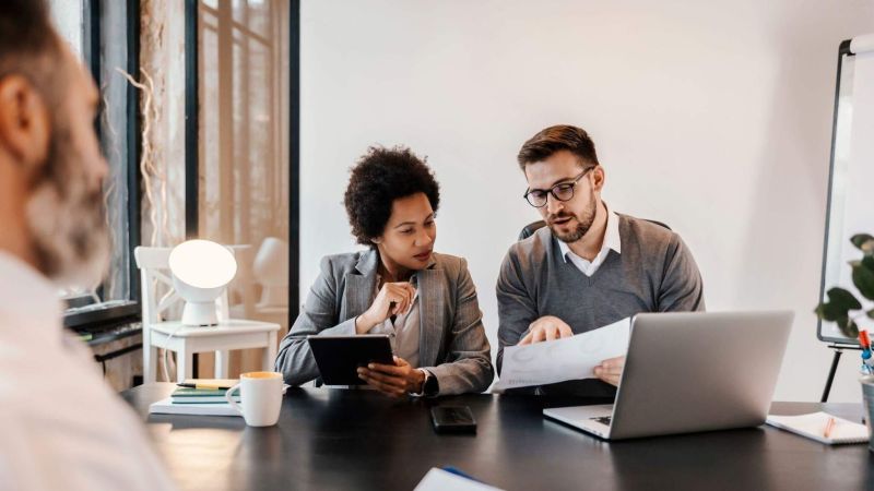 two people sitting at a table looking at a laptop