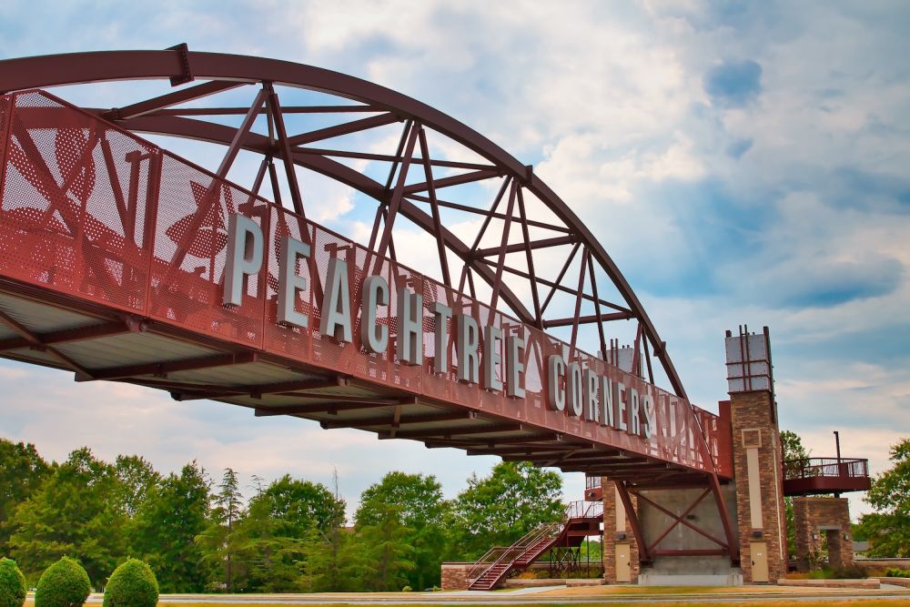 Peachtree Corners bridge structure against a cloudy blue sky in a scenic outdoor setting.