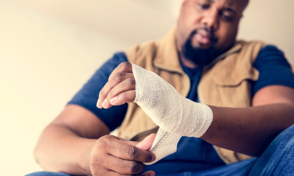 Man wrapping injured hand with bandage, focusing on self-care and injury recovery.