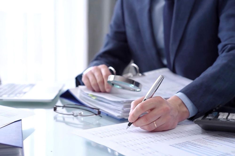 Business professional analyzing financial documents with a laptop and calculator on the desk.