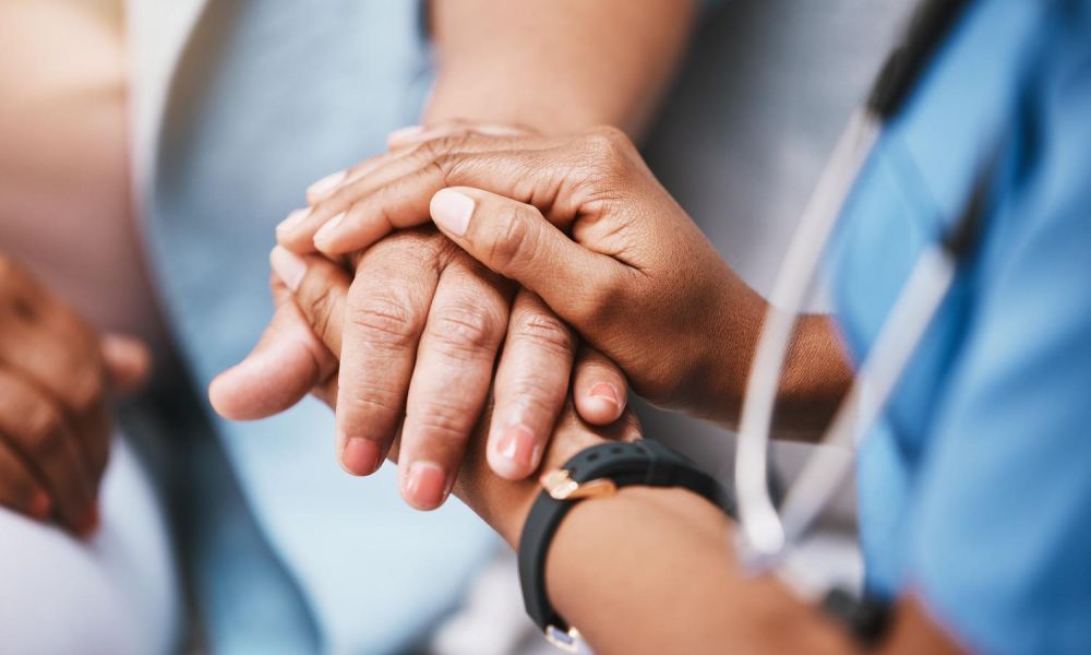 Two hands clasped together, showing compassion and support in a healthcare setting.