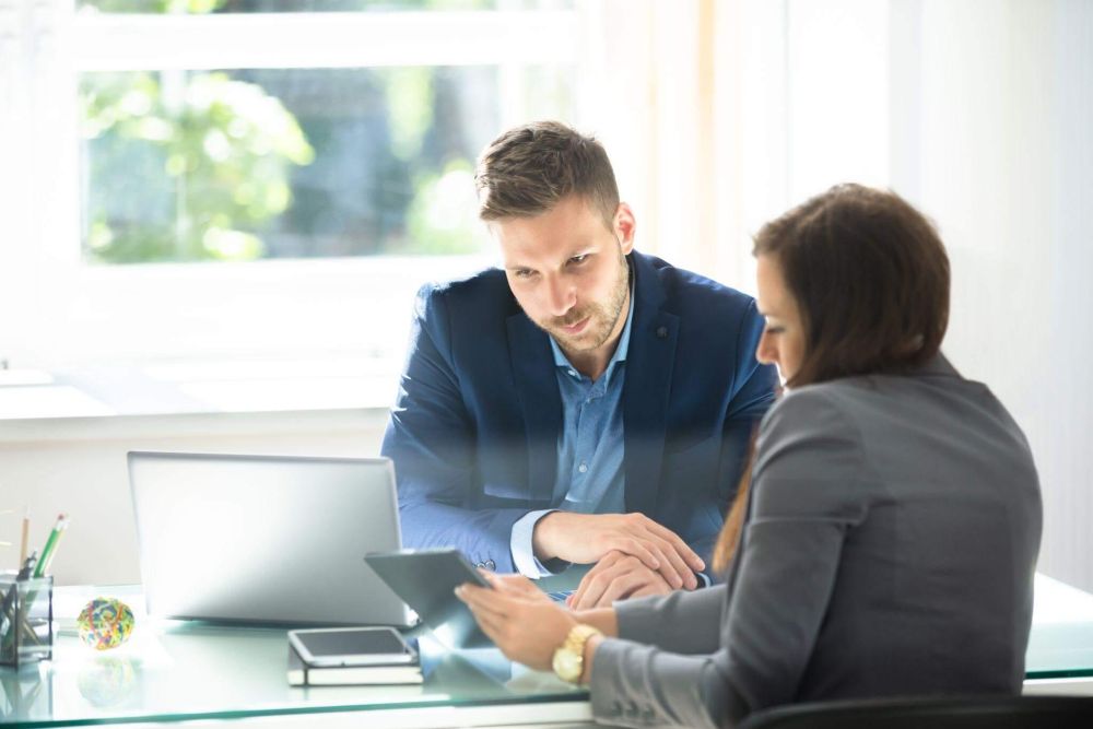 a man and woman sitting at a table looking at a tablet