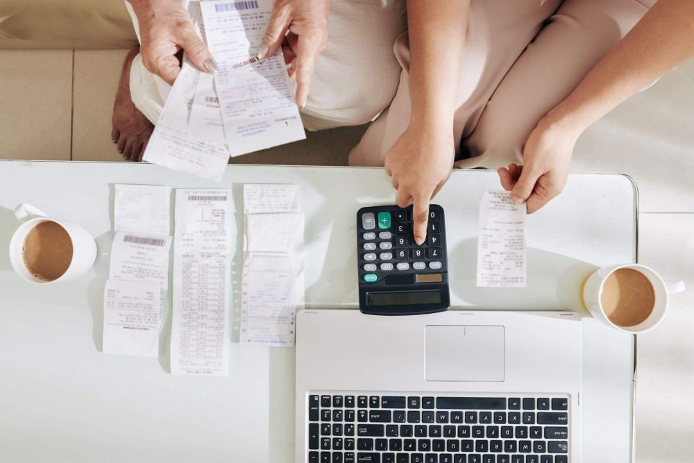 two people sitting at a desk with papers and a calculator