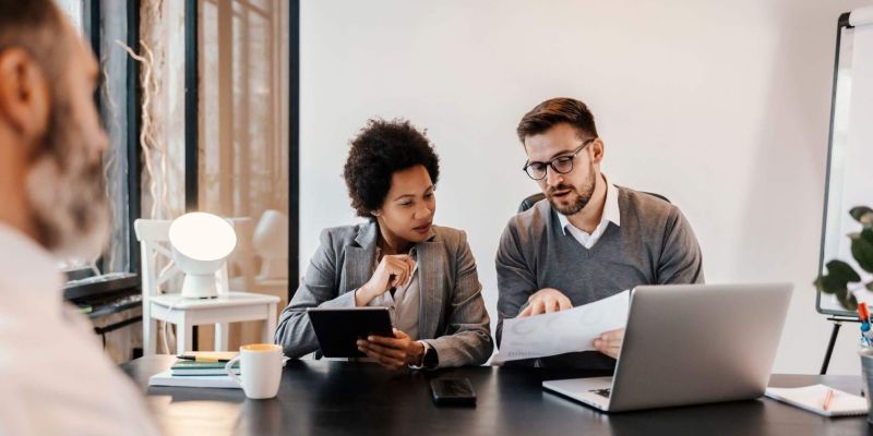 two people sitting at a table looking at a laptop