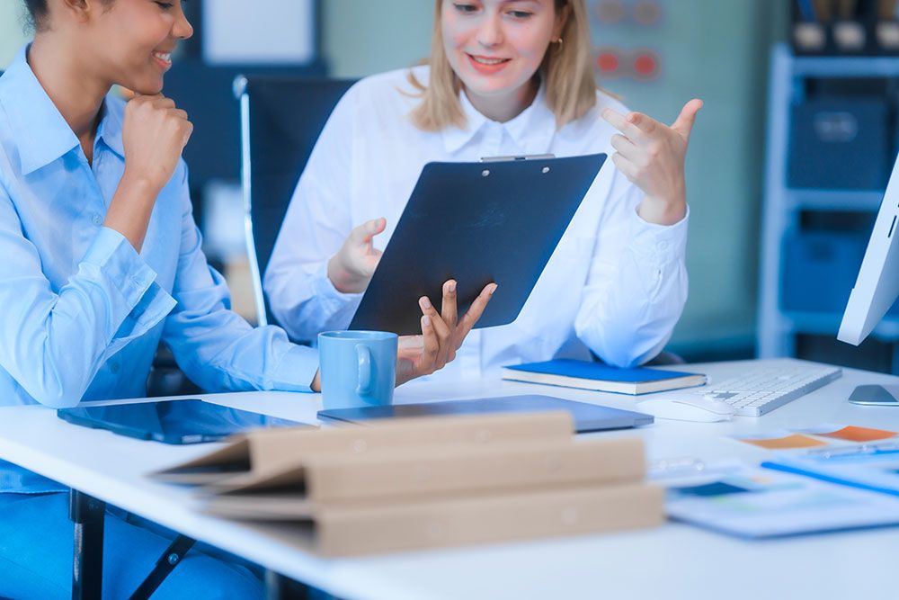 Two professionals discussing paperwork in a bright office setting.