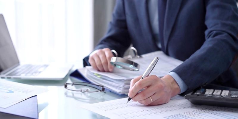 Business professional analyzing financial documents with a laptop and calculator on the desk.