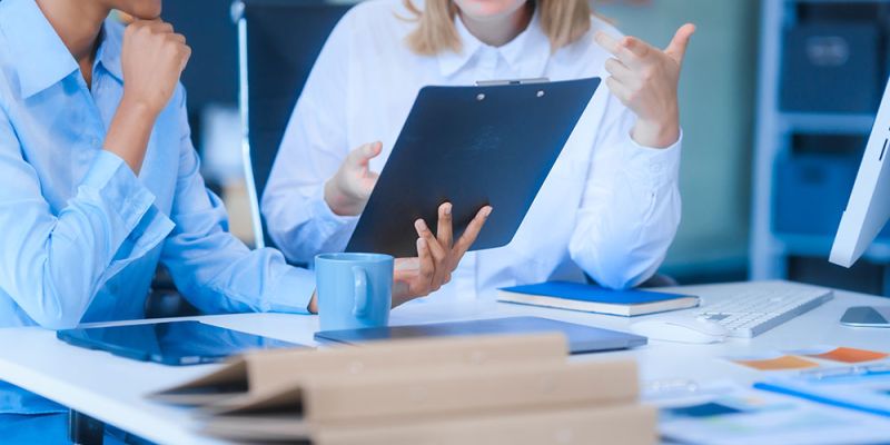 Two professionals discussing paperwork in a bright office setting.