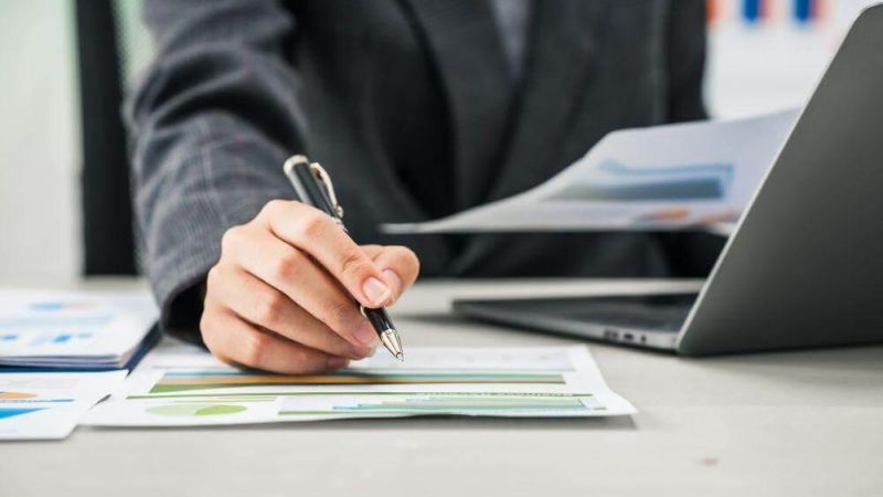 Person writing notes at a desk, relevant to CFO