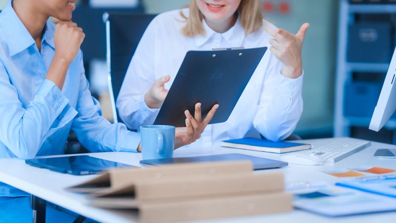 Two professionals discussing paperwork in a bright office setting.