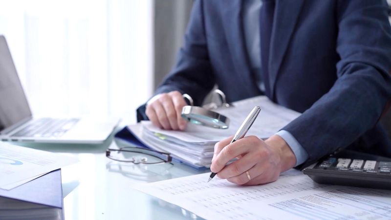 Business professional analyzing financial documents with a laptop and calculator on the desk.
