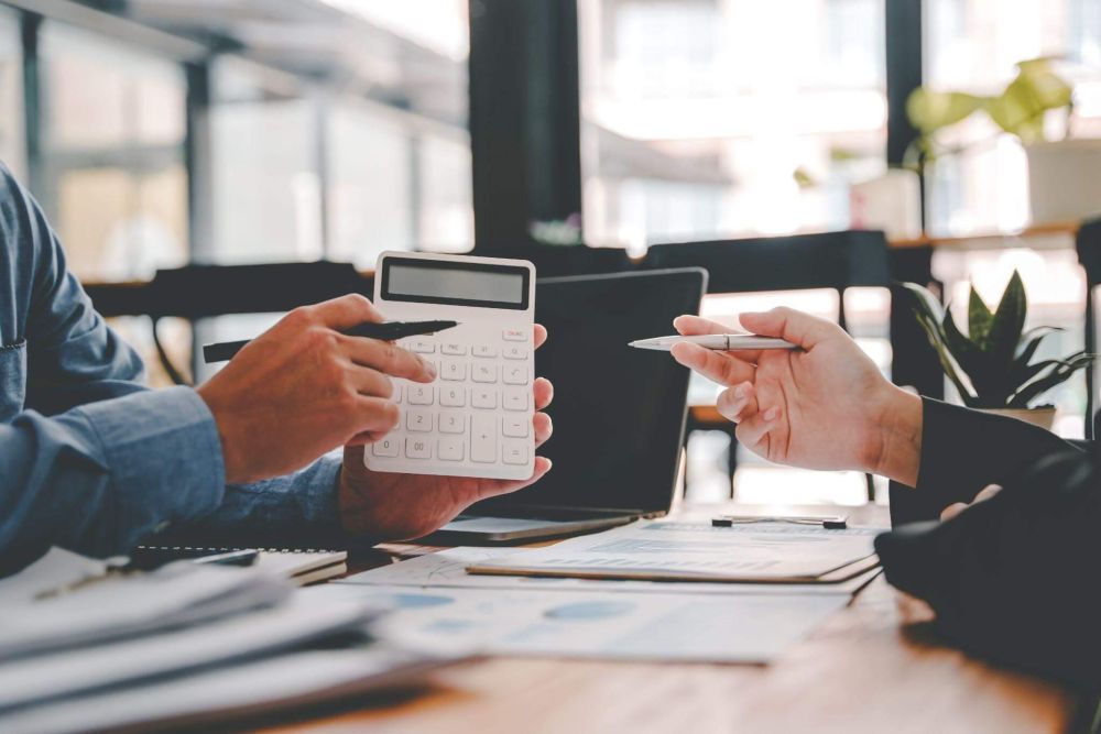 a couple of people sitting at a table with a calculator