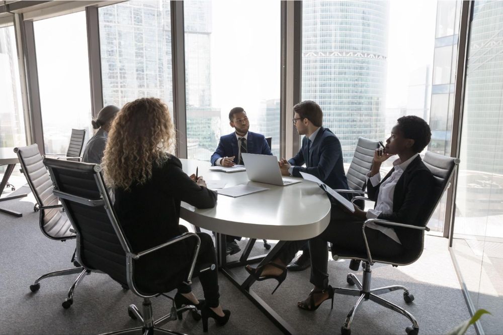 Professional business meeting in a modern office with diverse team discussing at a table.