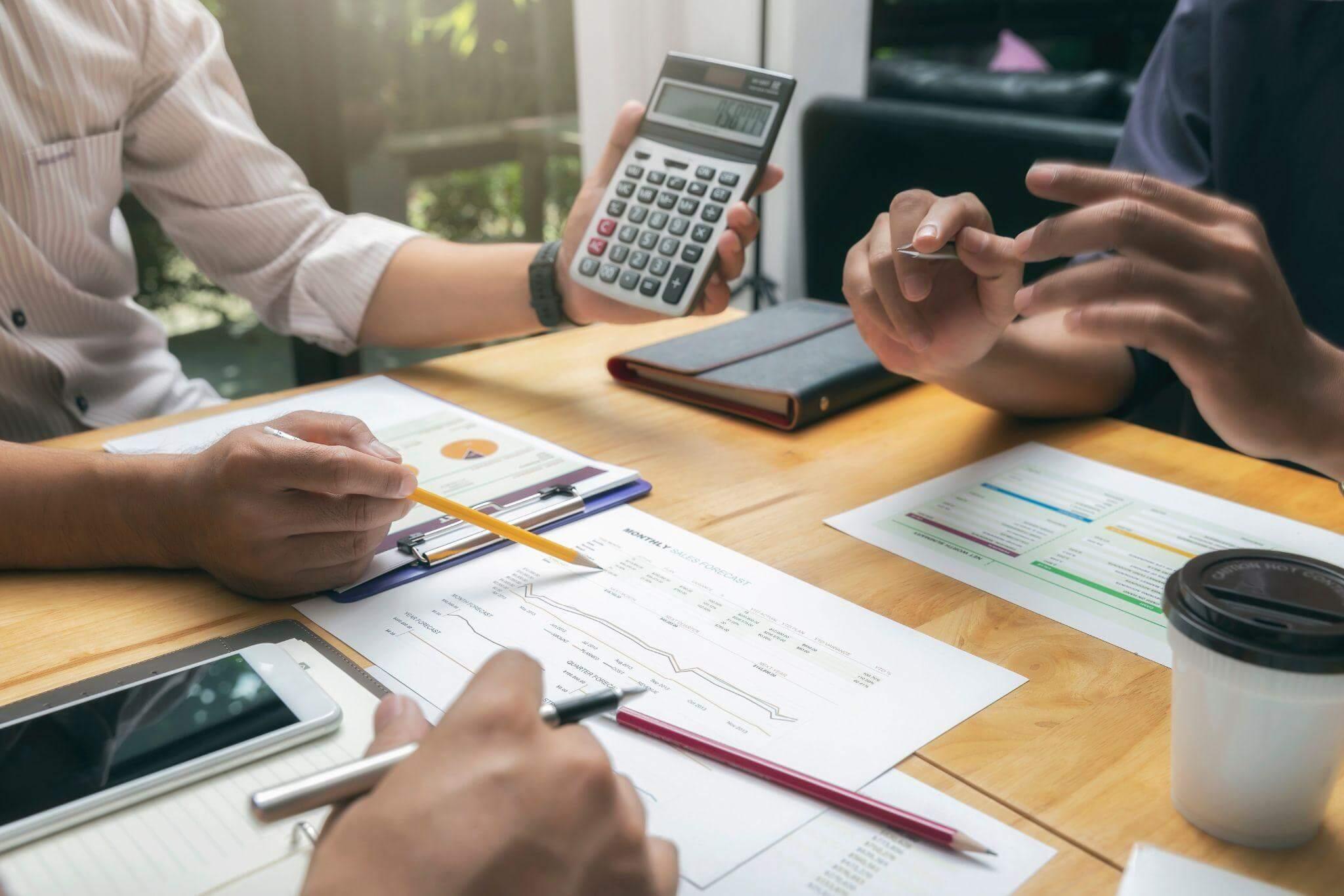 a couple of people sitting at a table with a calculator
