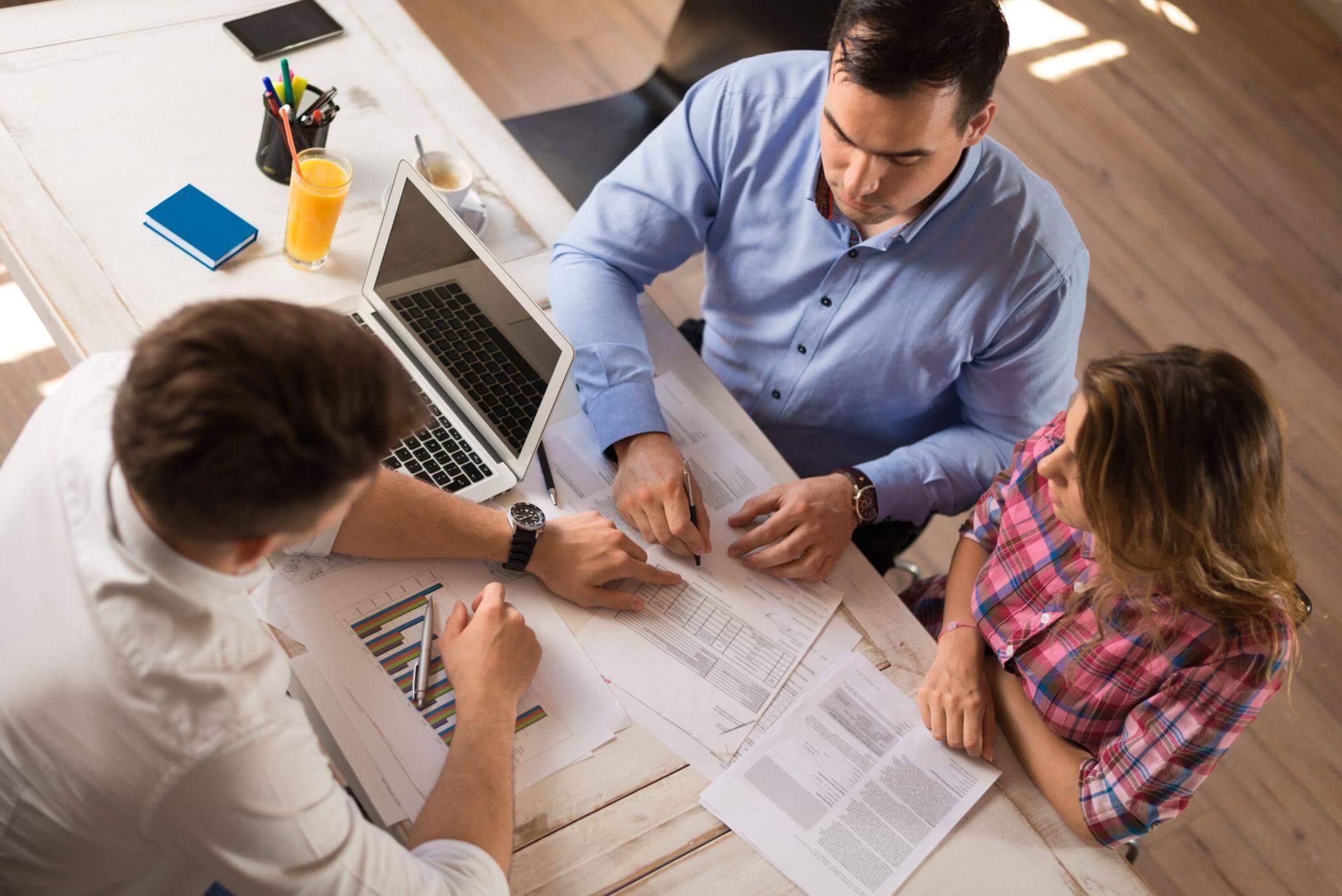 a man and a woman sitting at a table working on paperwork