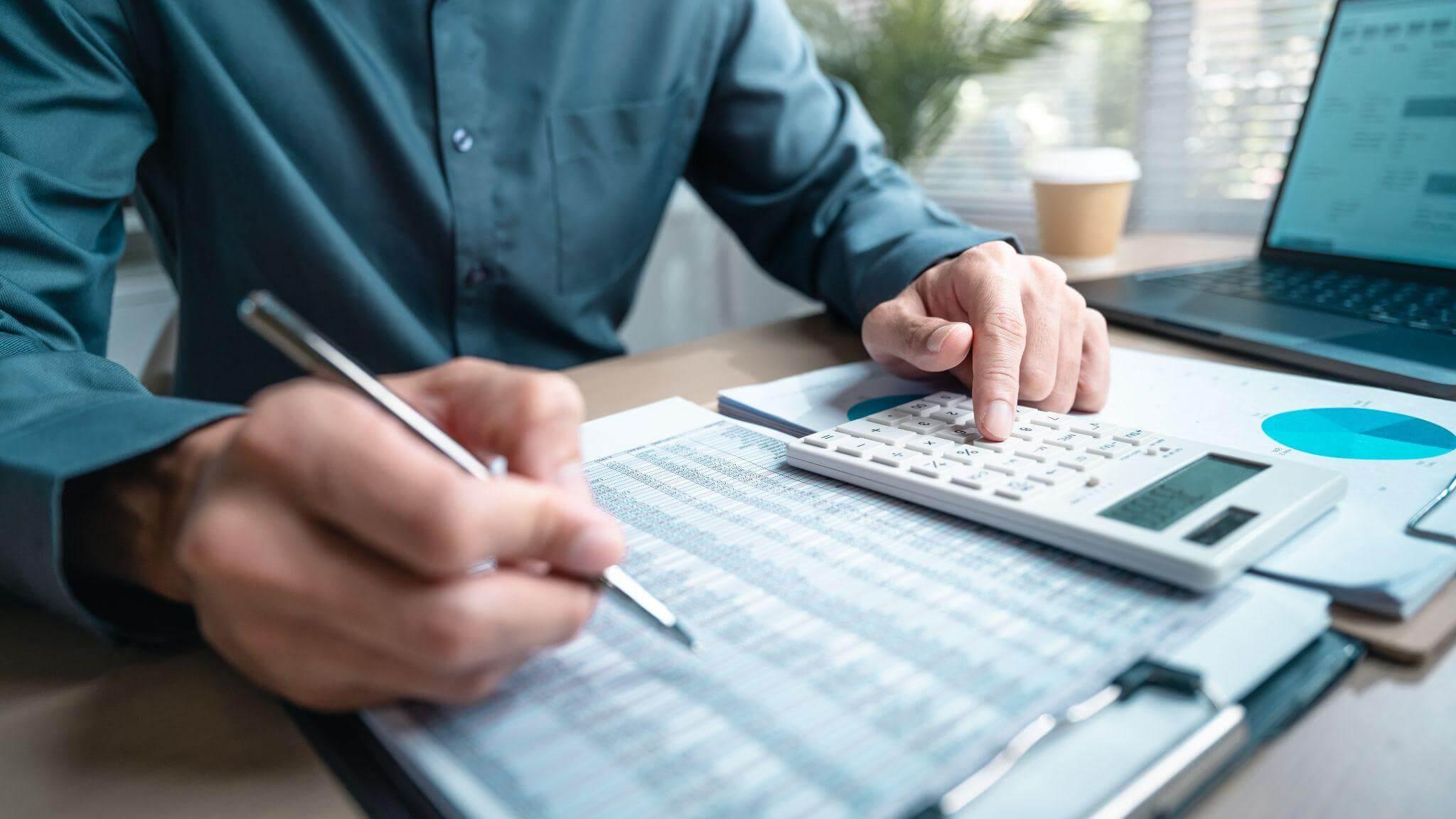 a man sitting at a desk with a calculator and pen