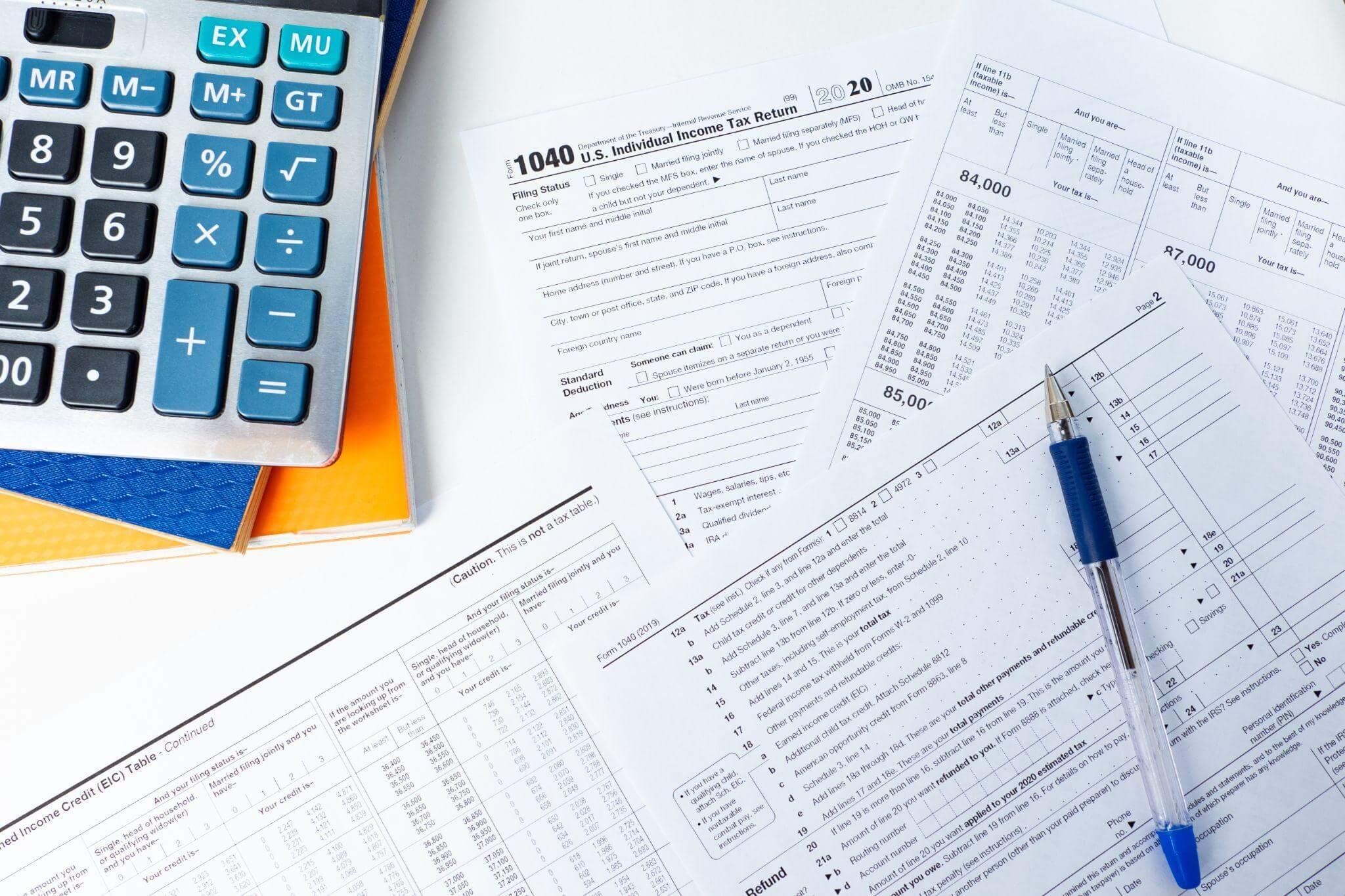 Calculator, pen, and paperwork on table for budgeting