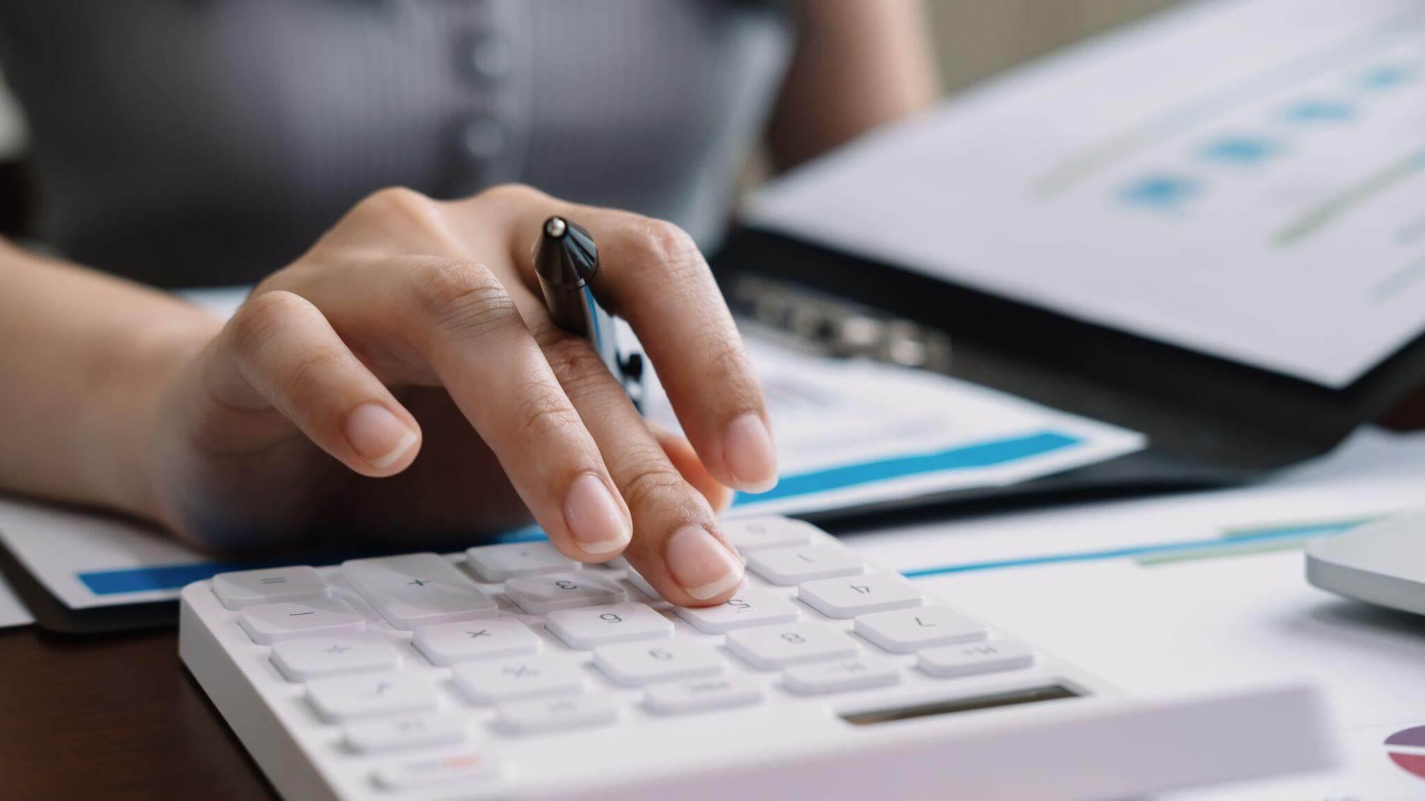 a woman is typing on a calculator at a desk