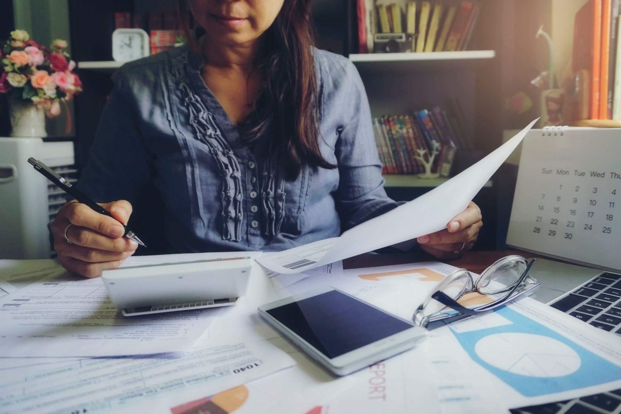 Woman at desk reviewing papers related to estimated taxes
